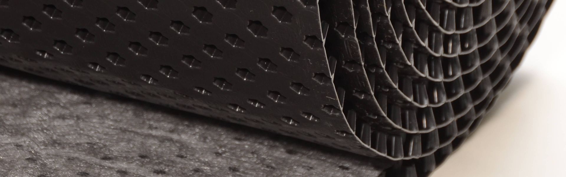 A roll of black rubber lies on a white surface.